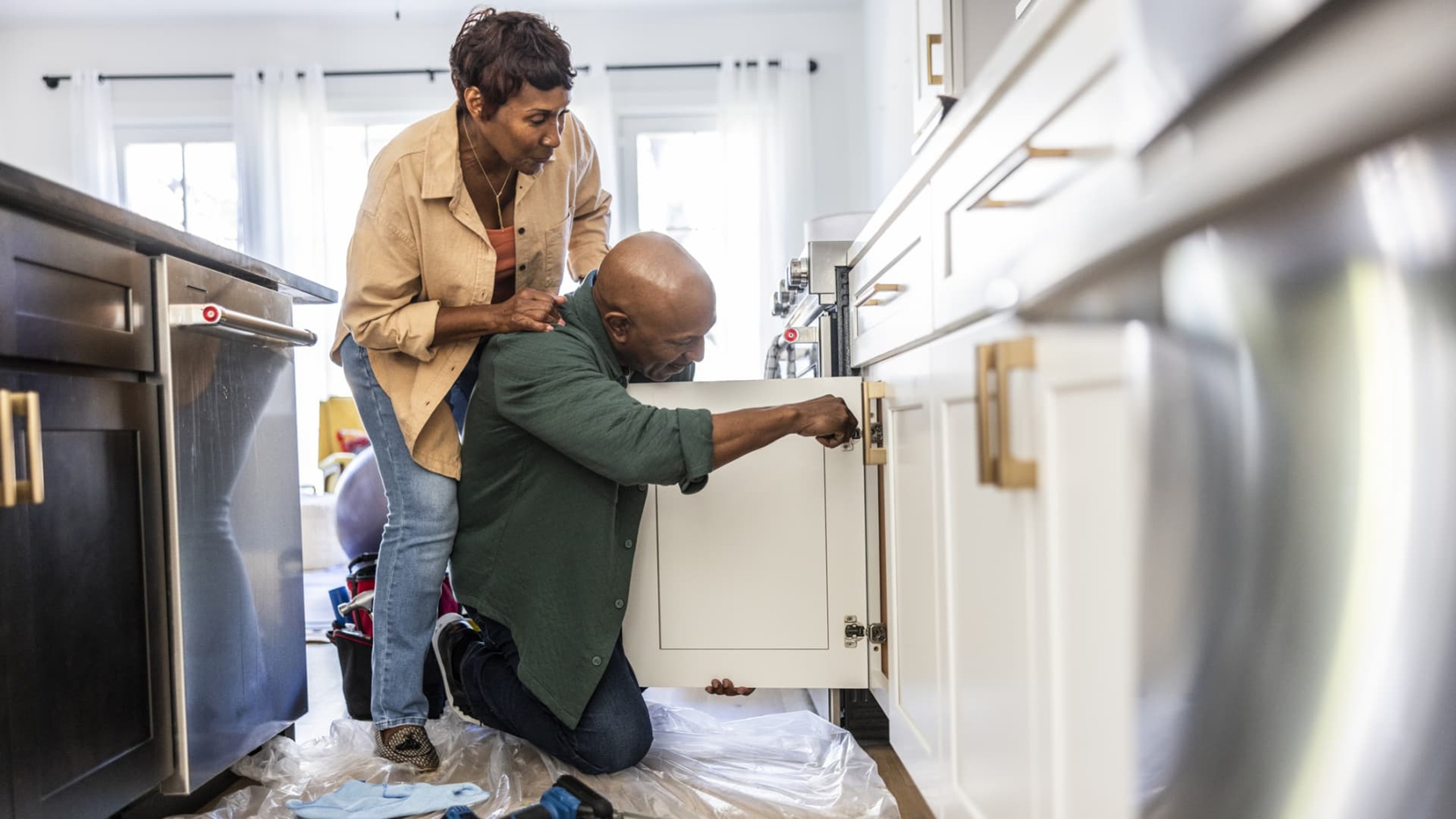 couple repairing kitchen cabinet